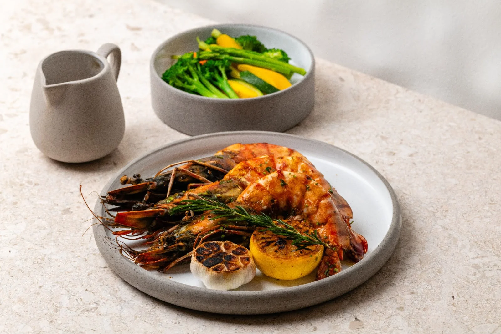 Grilled shrimp served with lemon and vegetables on grey ceramic